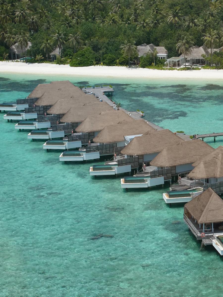 Aerial view of the resort's largest overwater villa, its thatched roof and private pool set at the end of the jetty.
