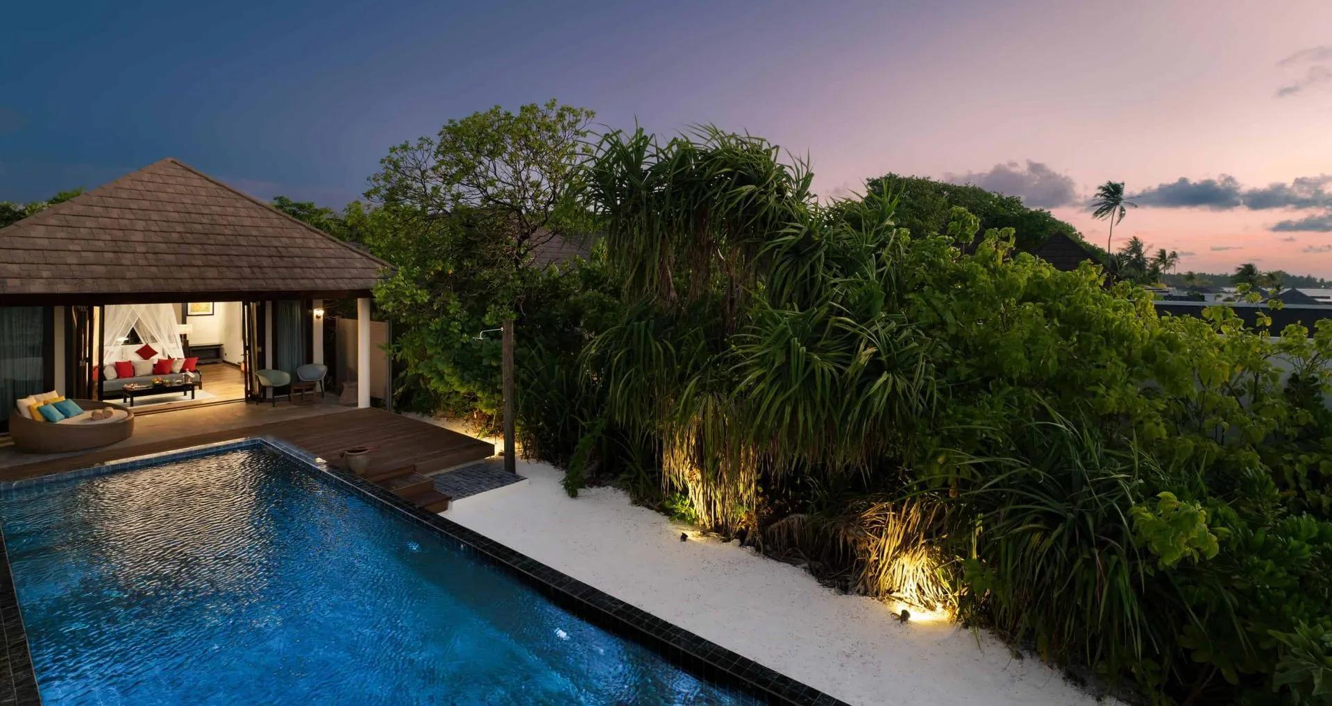 A Kanifushi Beach Villa with Pool at dusk, its private pool lit beside the villa