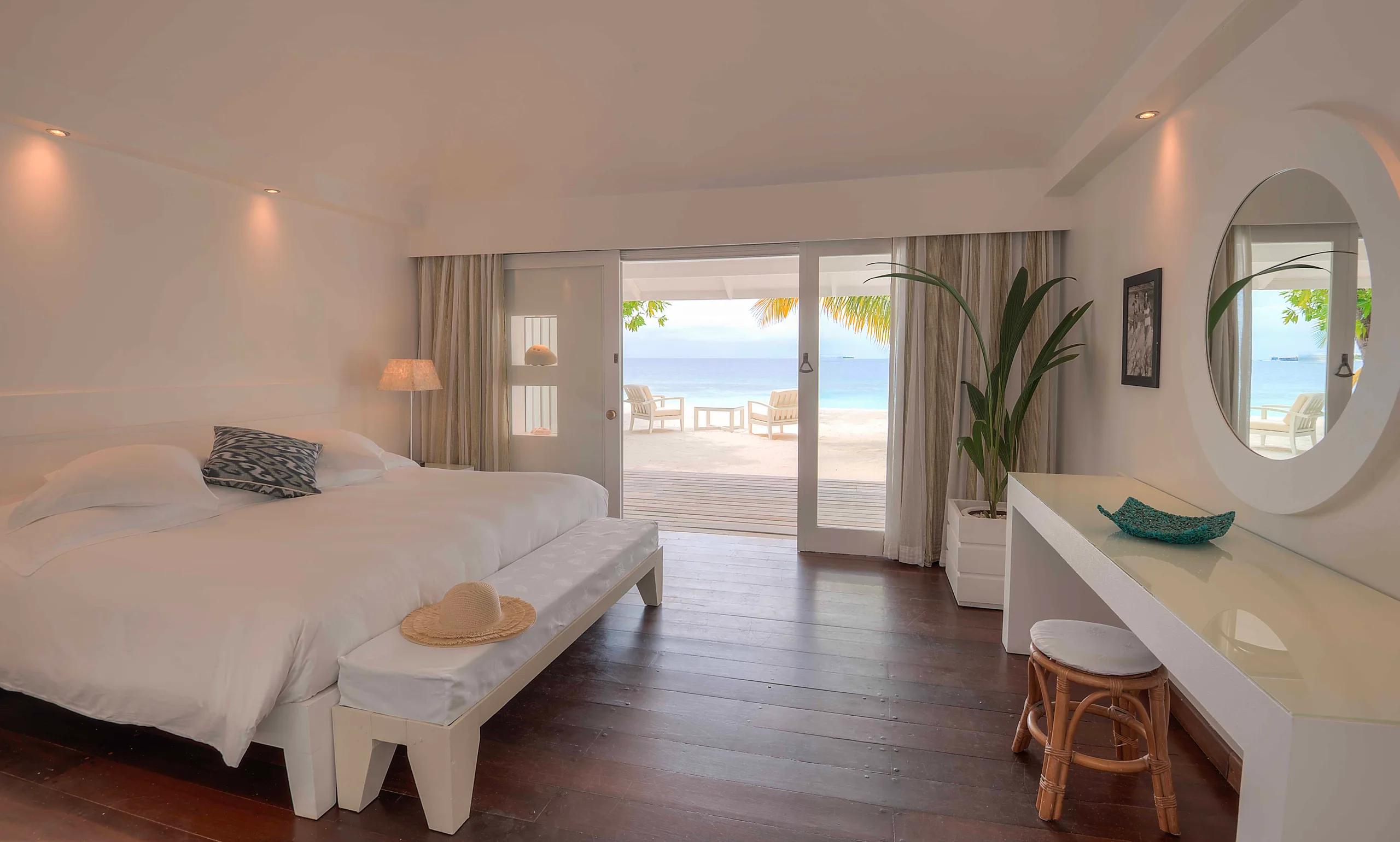 A beach-category bedroom interior with a round mirror and sea view through the doorway — standing in for Beach Suites, which has no dedicated photography yet