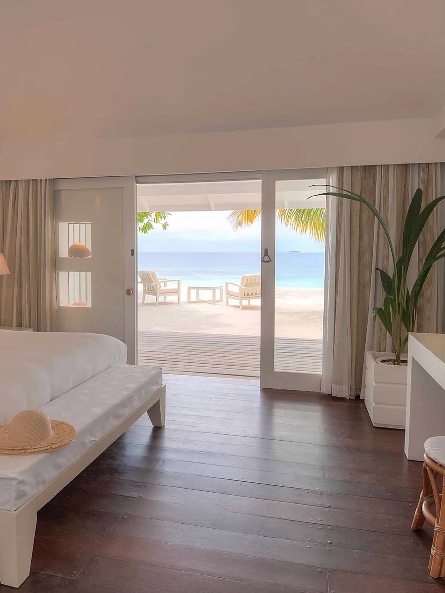 A beach-category bedroom interior with a round mirror and sea view through the doorway — standing in for Beach Suites, which has no dedicated photography yet