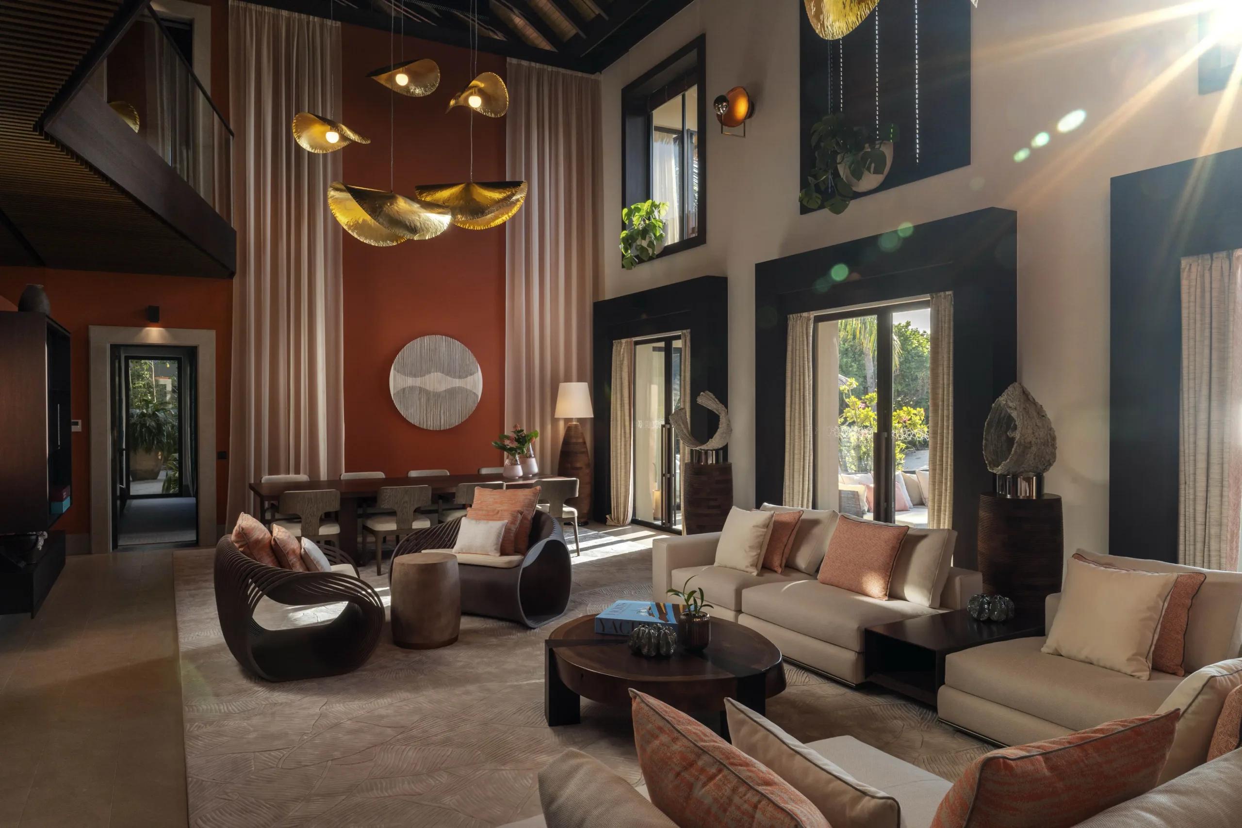 A high-ceilinged living and dining space inside Kuredhi Private Residence, with a mezzanine level above