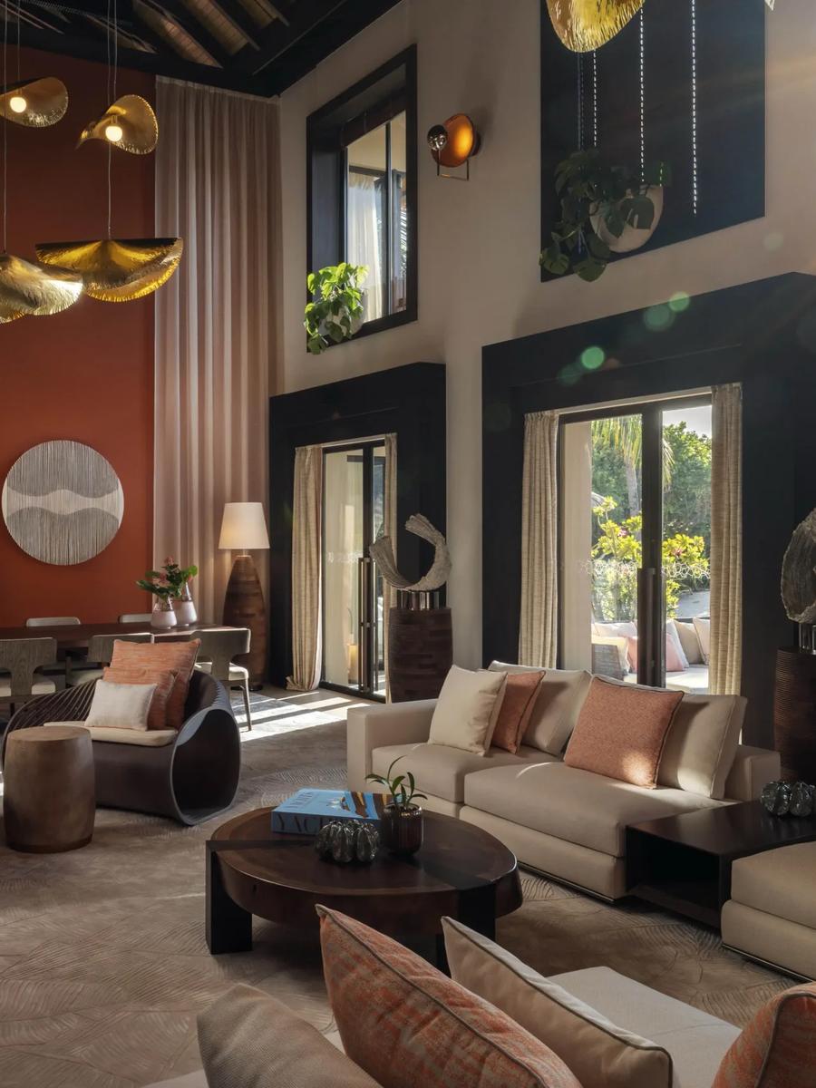 A high-ceilinged living and dining space inside Kuredhi Private Residence, with a mezzanine level above
