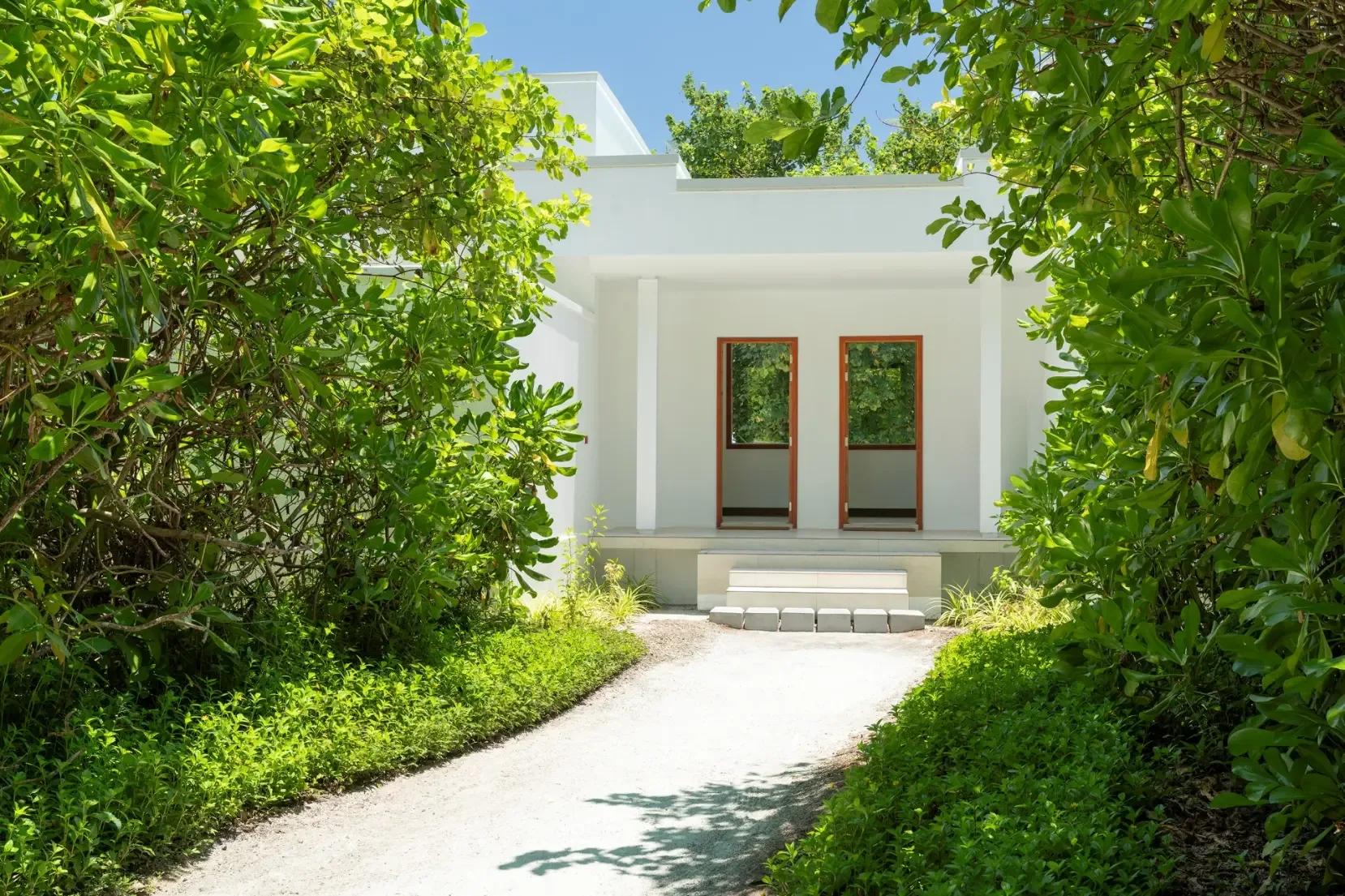 The white gravel entrance path to a Two-Bedroom Beach Villa, framed by dense tropical planting