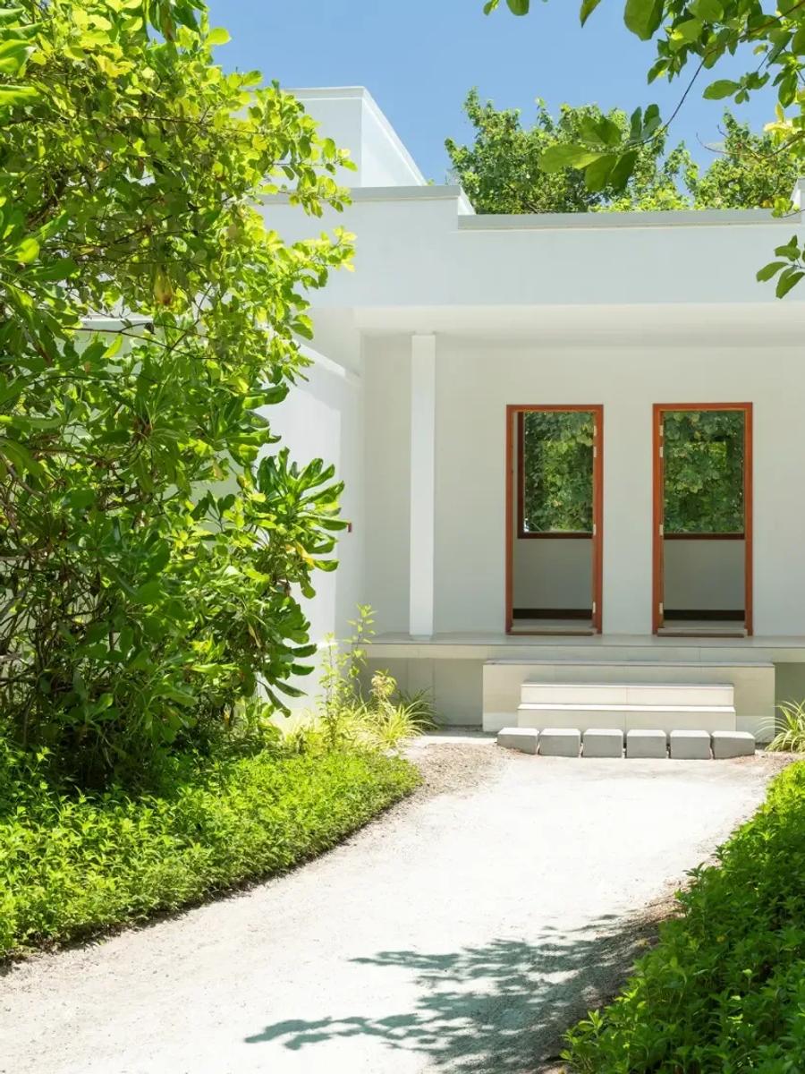 The white gravel entrance path to a Two-Bedroom Beach Villa, framed by dense tropical planting