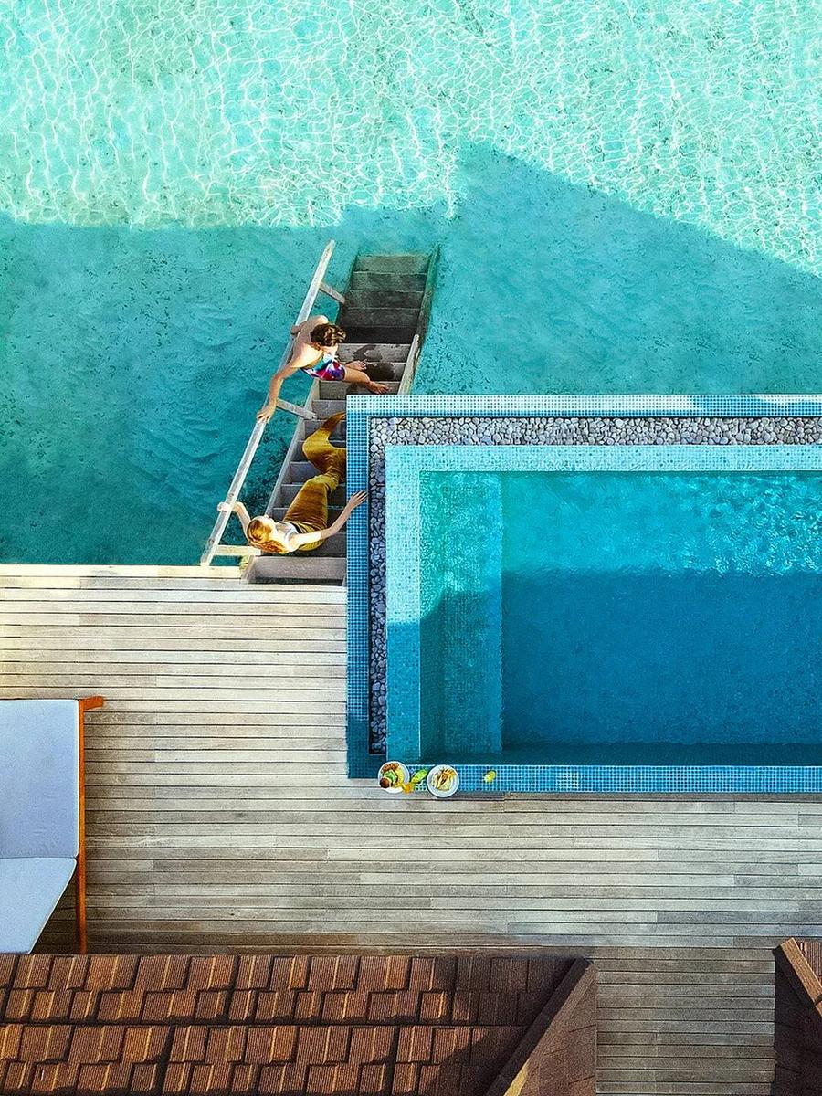 Two guests jumping into the shared plunge pool of a Two Bedroom Lagoon Overwater Villa, seen from directly above