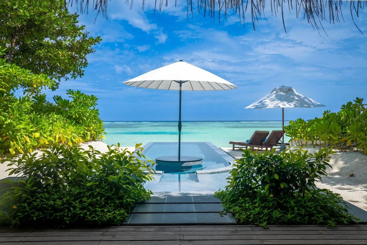 A Beachfront Infinity Pool Villa's private pool, framed by beach umbrellas with the lagoon beyond