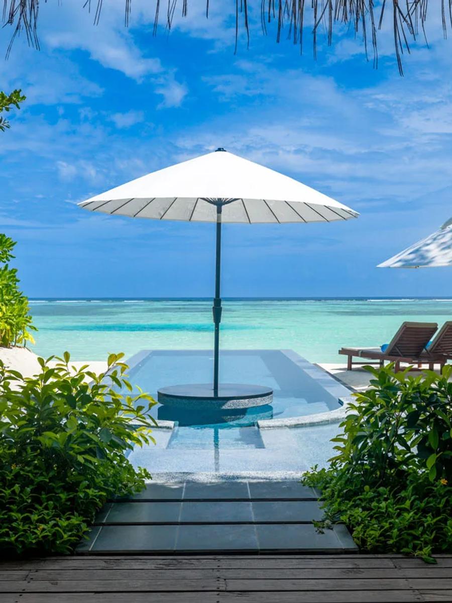 A Beachfront Infinity Pool Villa's private pool, framed by beach umbrellas with the lagoon beyond