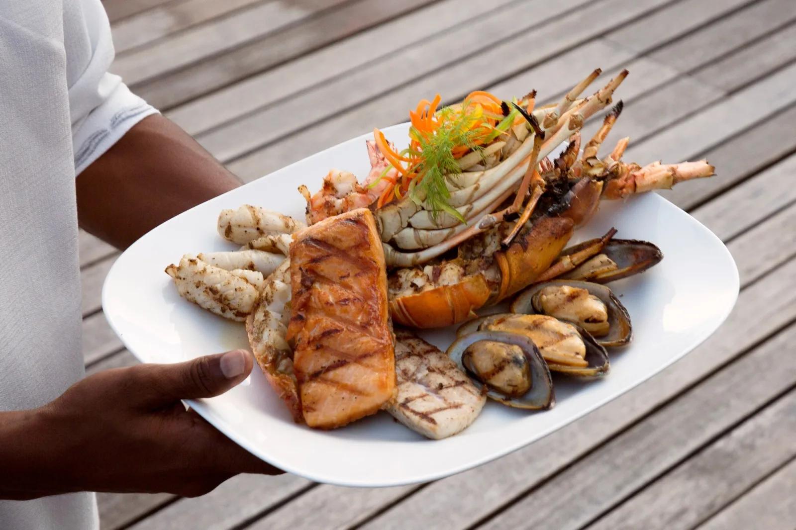 A grilled seafood platter of lobster, salmon, mussels and prawns presented tableside