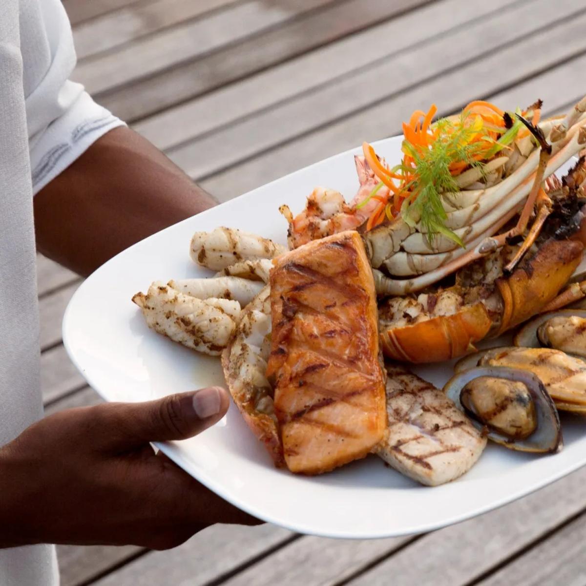 A grilled seafood platter of lobster, salmon, mussels and prawns presented tableside