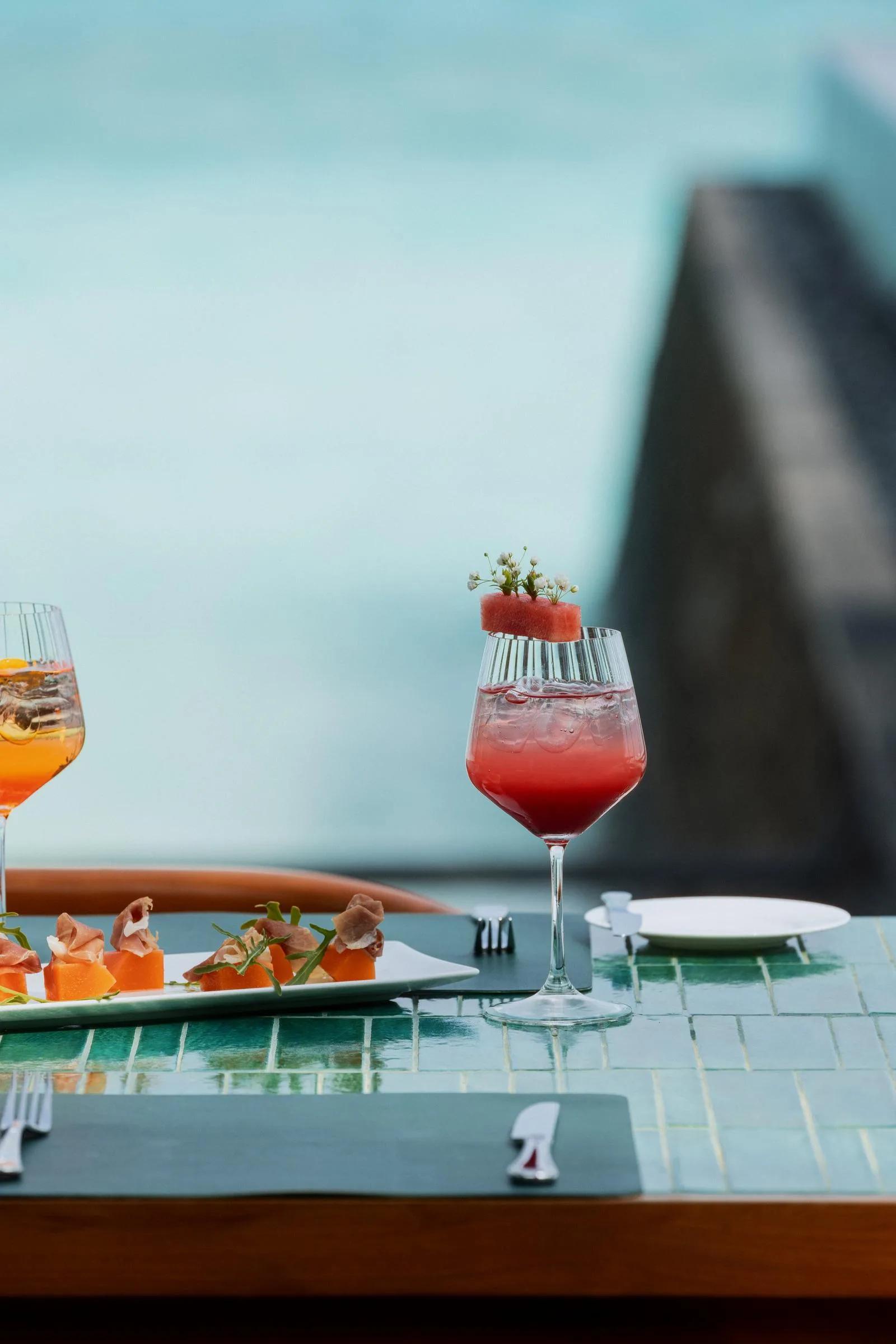 A glass of rosé and a melon-and-prosciutto starter set poolside at One&Only Reethi Rah — standing in for Private Dining, the resort's bespoke destination-dining service, since no dedicated photograph was collected