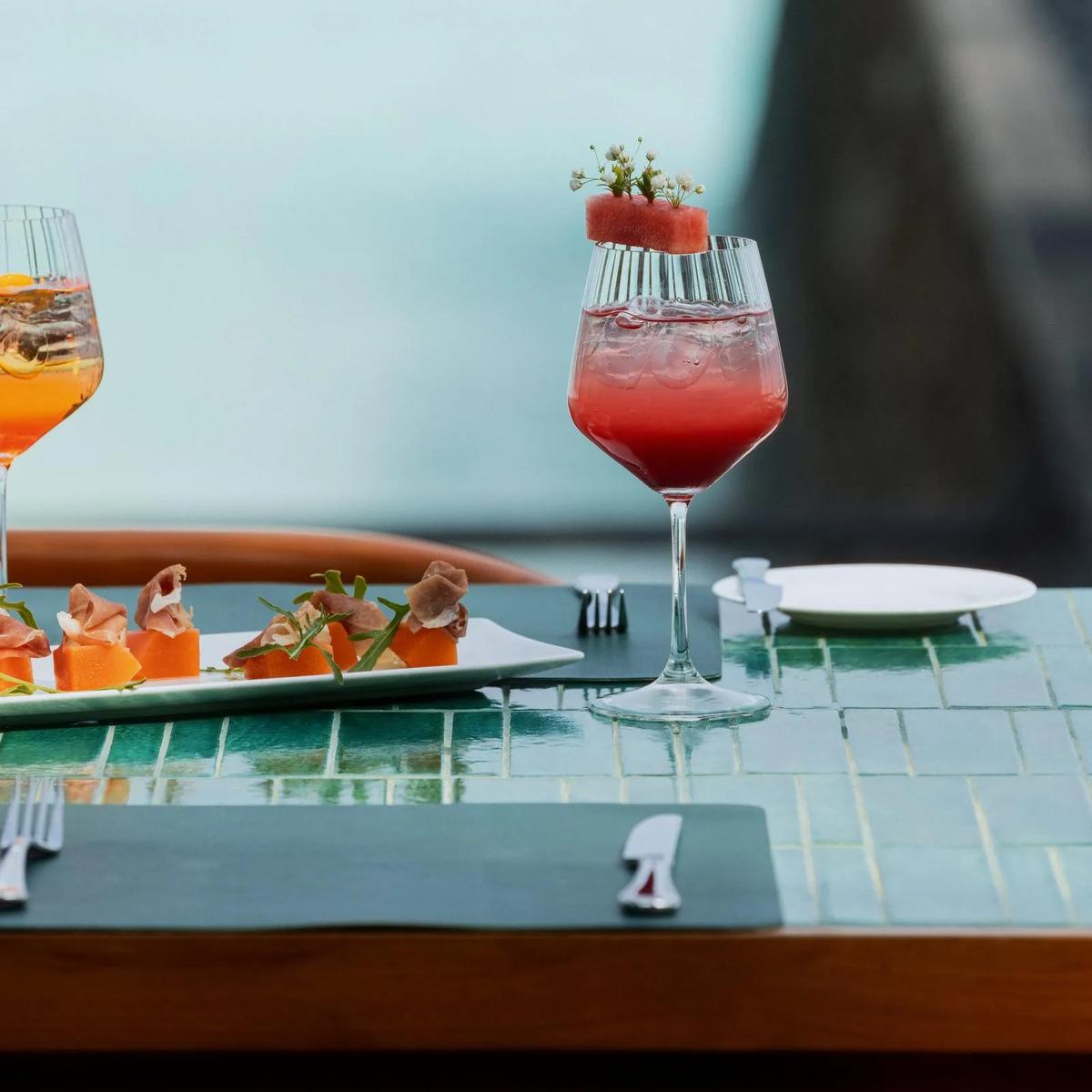 A glass of rosé and a melon-and-prosciutto starter set poolside at One&Only Reethi Rah — standing in for Private Dining, the resort's bespoke destination-dining service, since no dedicated photograph was collected