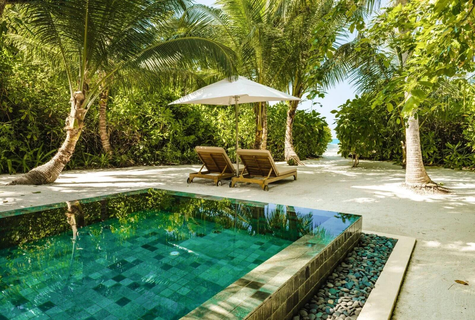 A One-Bedroom Sunset Beach Pool Villa's private pool and sun loungers under palm trees, steps from the beach