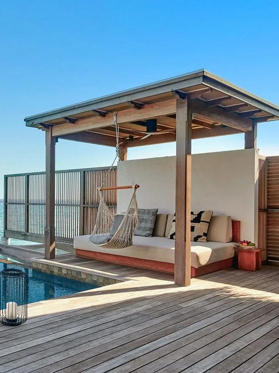 Overwater deck of a water villa with a private plunge pool, sun loungers and umbrella, open ocean beyond