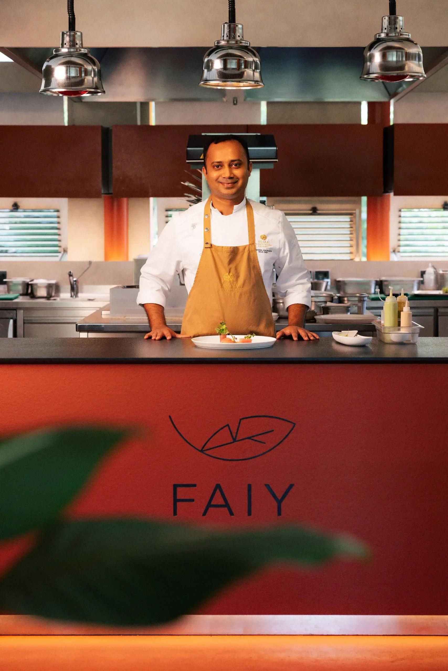 A chef stands behind the open kitchen counter at Faiy, a single plated dish set in front of him