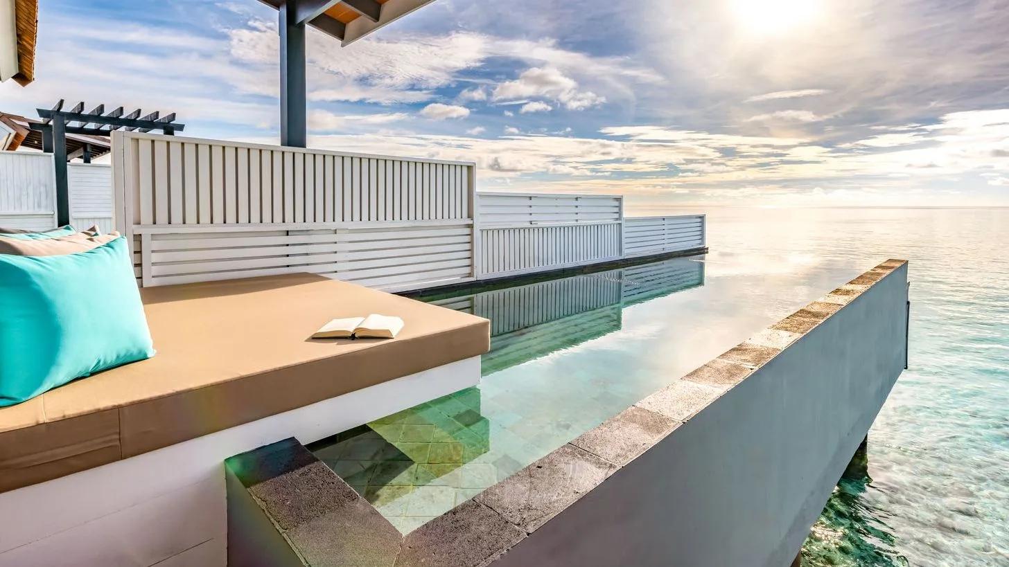 The plunge-pool deck of a Wind Villa with Pool, a daybed with turquoise cushions facing the open ocean