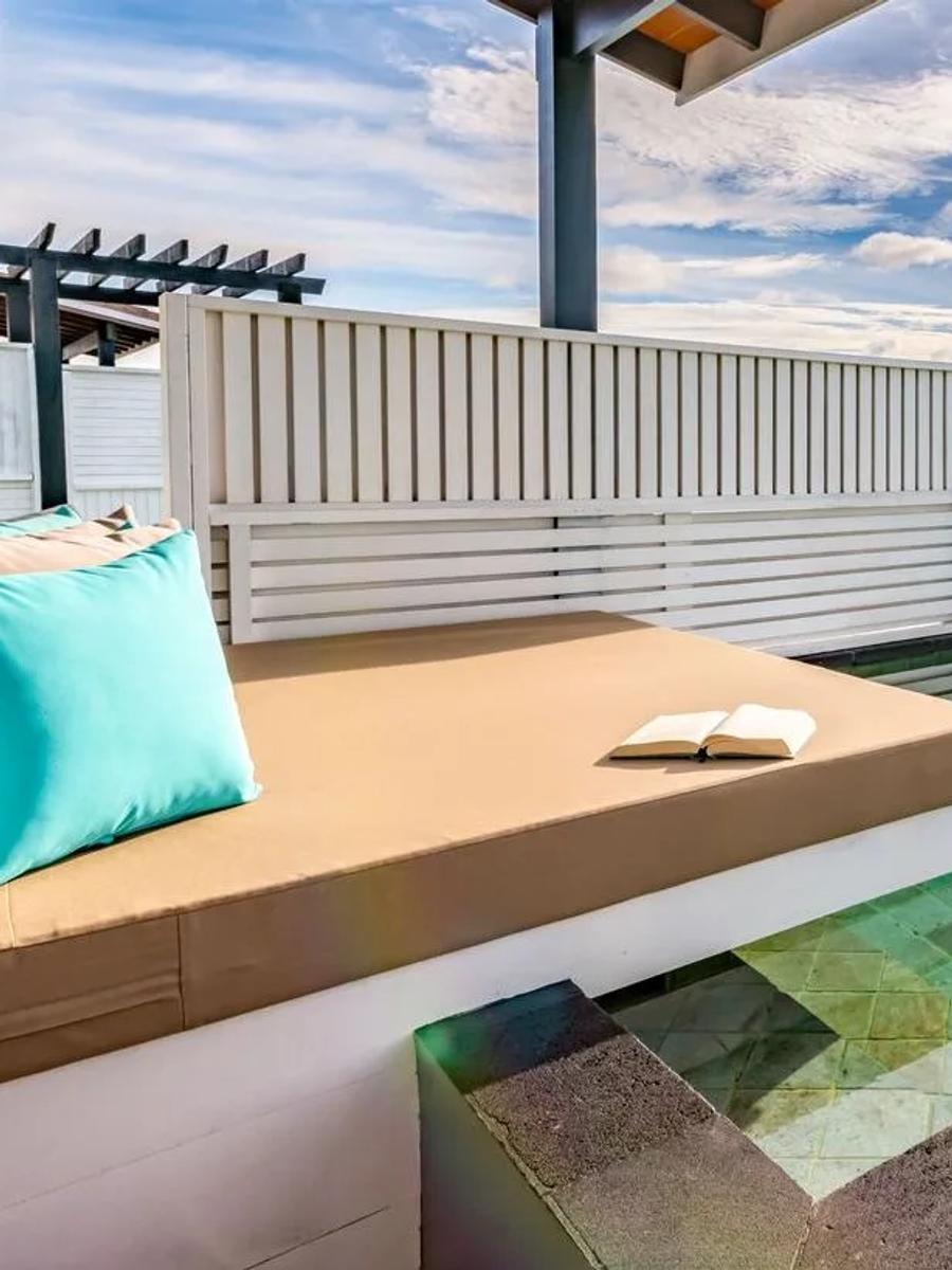 The plunge-pool deck of a Wind Villa with Pool, a daybed with turquoise cushions facing the open ocean