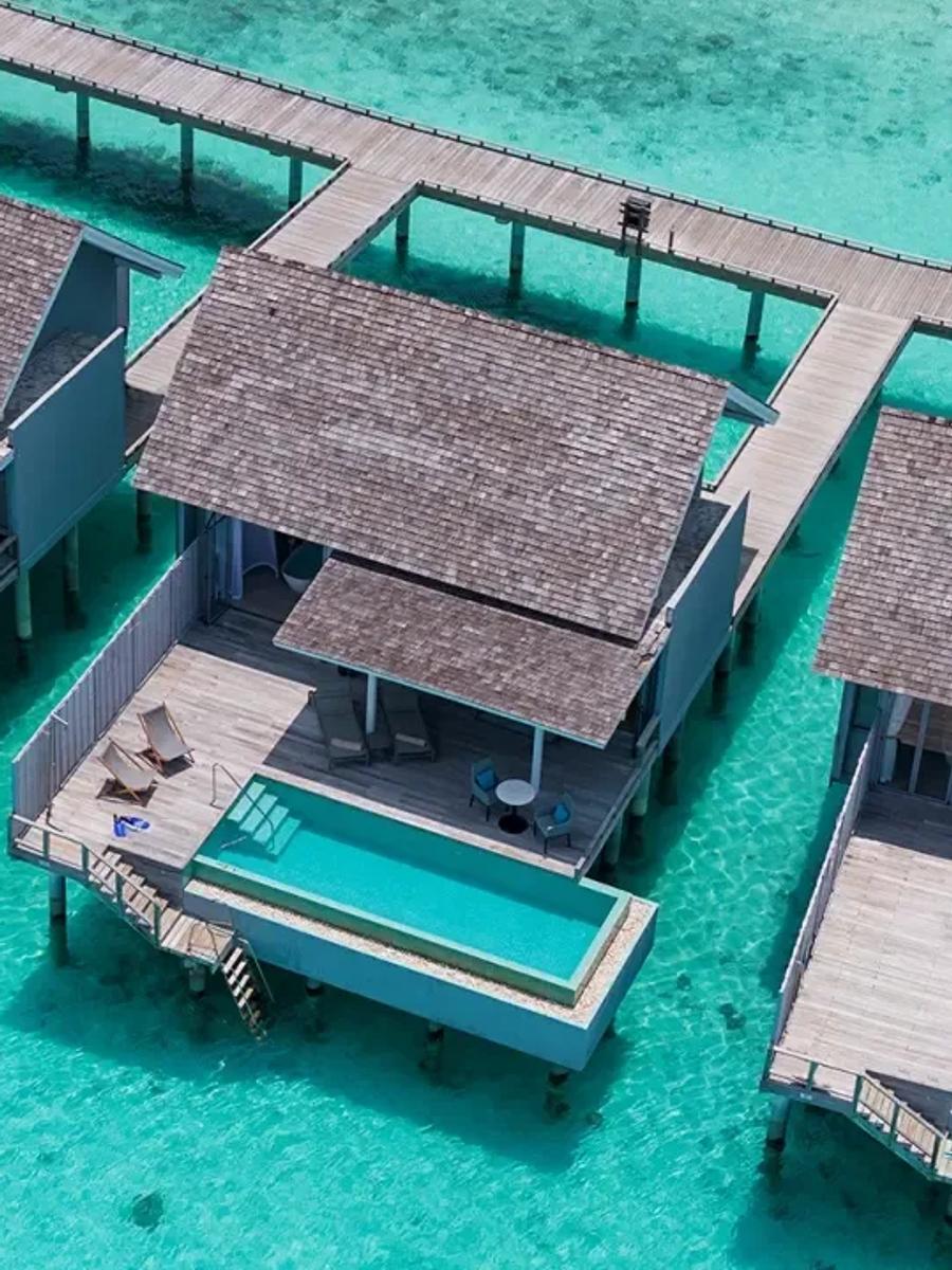 Aerial view of Water Villa with Pool units over the lagoon, each with a private plunge pool and a curving wooden jetty connecting them