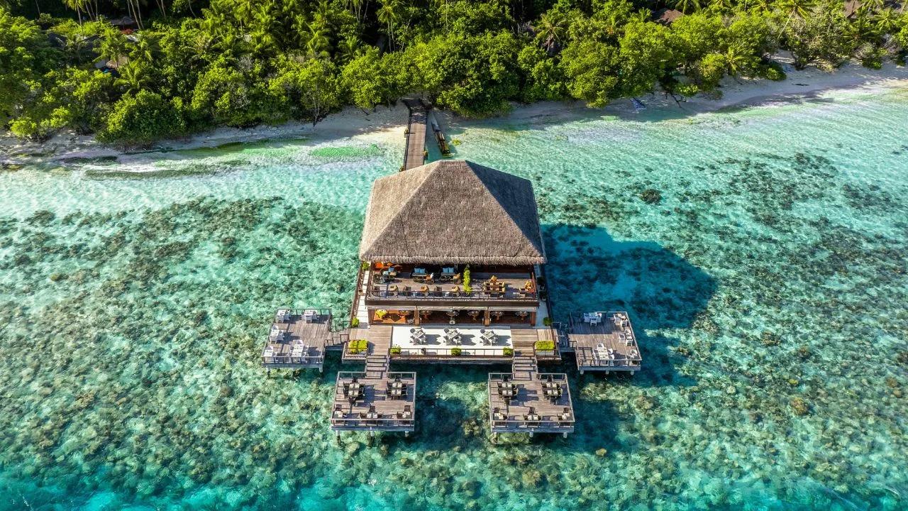 The overwater dining terrace at Dusit Thani Maldives — the resort has not published a dedicated photograph of The Market, its main buffet restaurant; this overwater dining scene stands in
