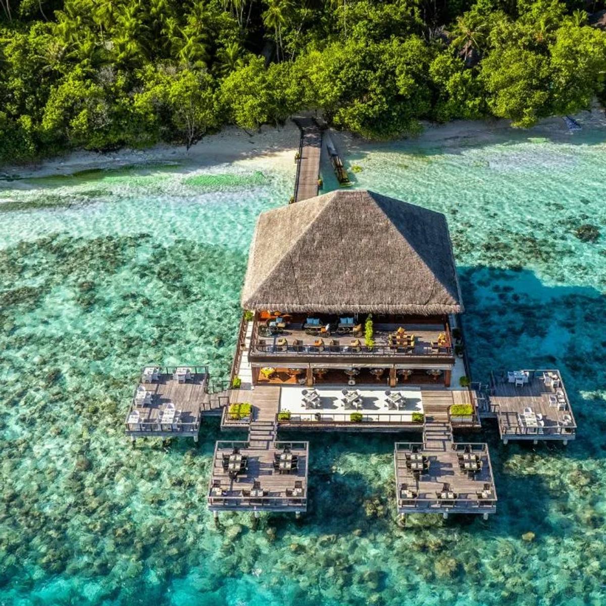 The overwater dining terrace at Dusit Thani Maldives — the resort has not published a dedicated photograph of The Market, its main buffet restaurant; this overwater dining scene stands in
