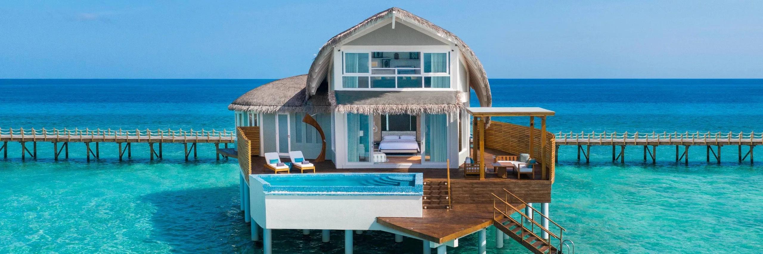 The two-story Duplex Overwater Pool Villa seen from the water, its private pool on the lower deck and the upstairs lounge windows above