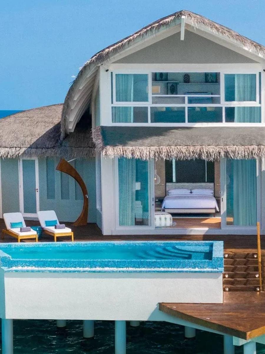 The two-story Duplex Overwater Pool Villa seen from the water, its private pool on the lower deck and the upstairs lounge windows above