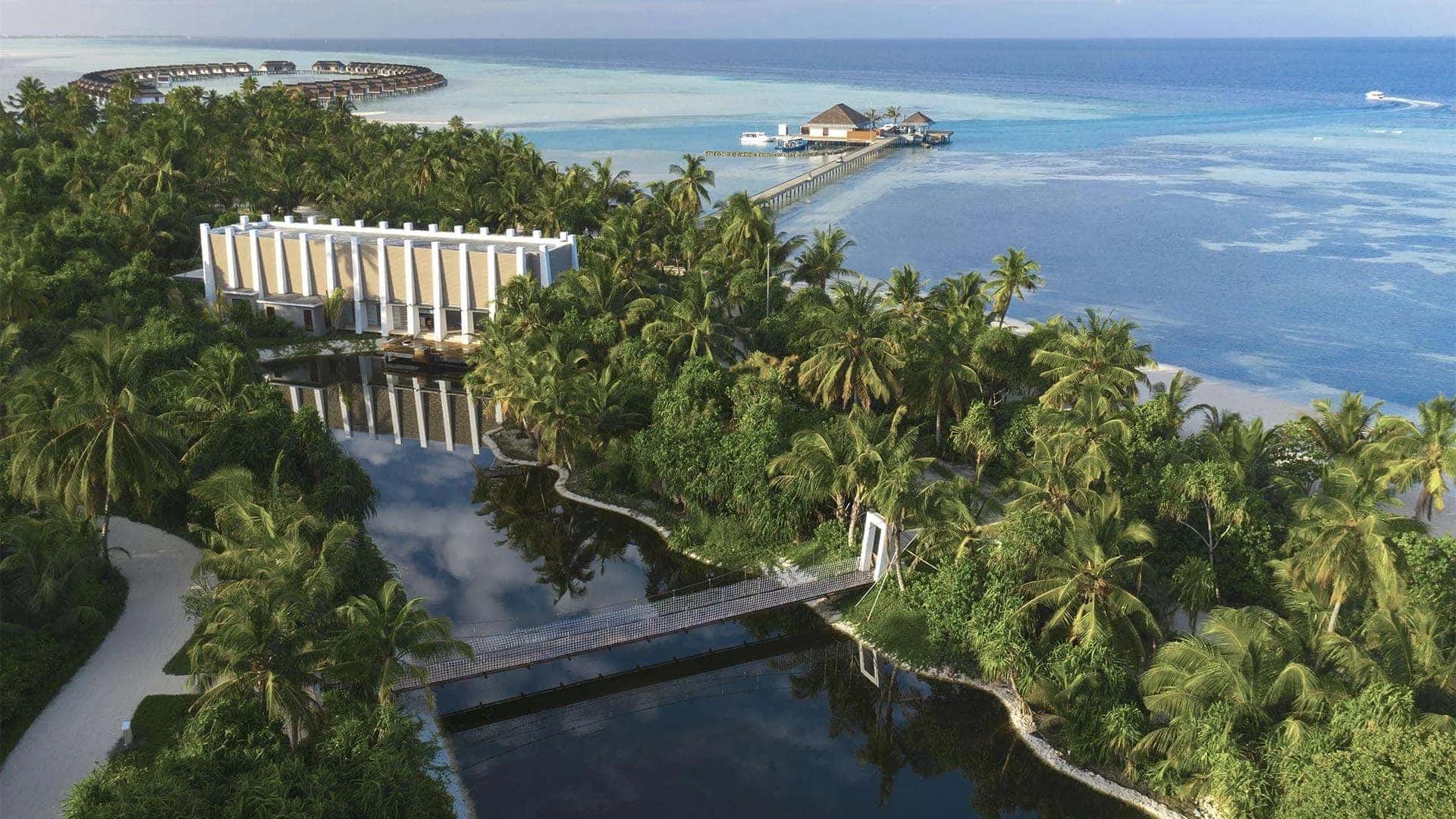 Aerial view of Pullman Maldives Maamutaa's private island, its overwater villas and the natural lake bridge crossing the lagoon in Gaafu Alifu Atoll