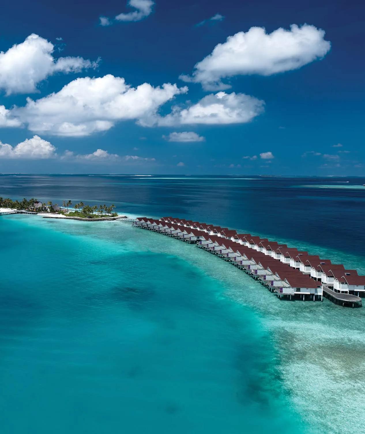 A vertical aerial view of OBLU SELECT Lobigili's water villa jetty curving out over the reef, North Malé Atoll