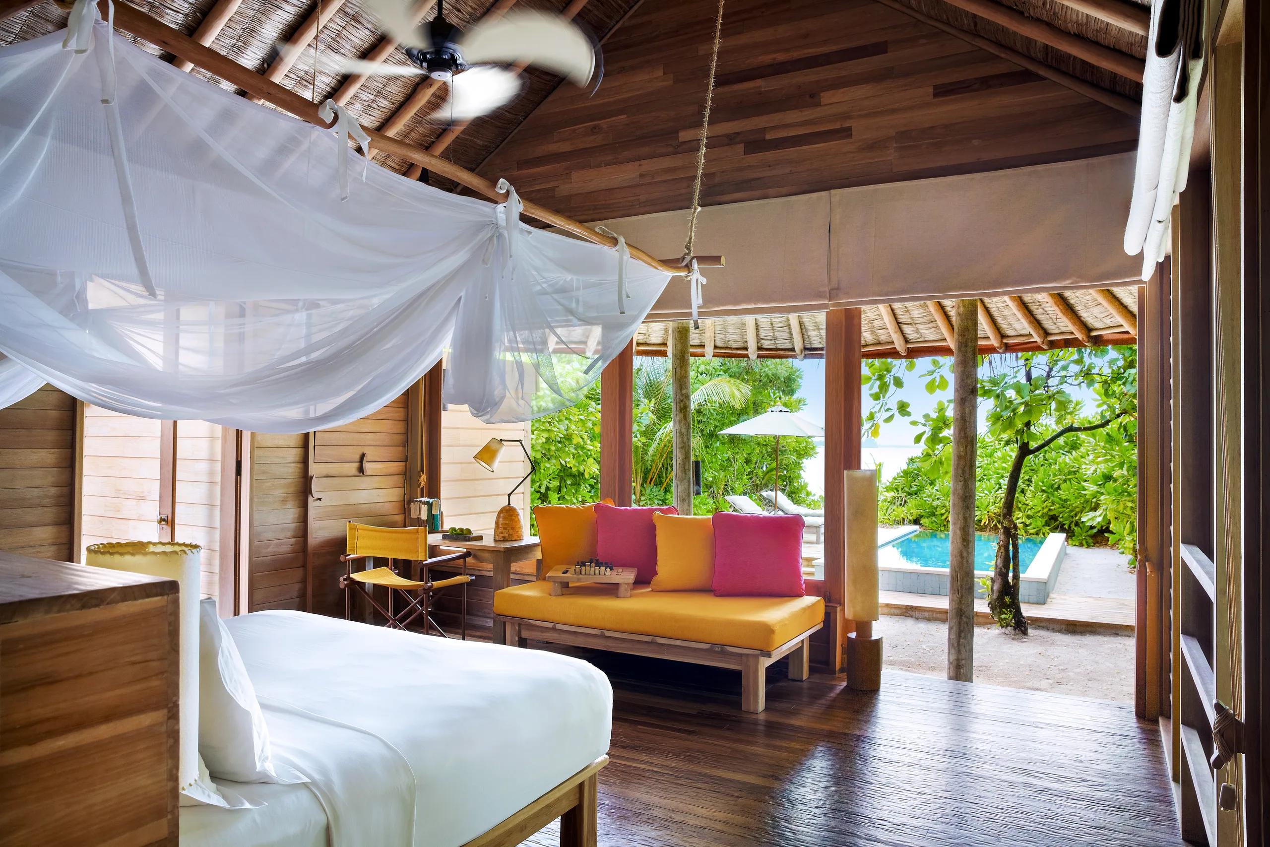 A ceiling fan turning beneath a thatched roof inside a beach villa with pool, representative of the lagoon-side category