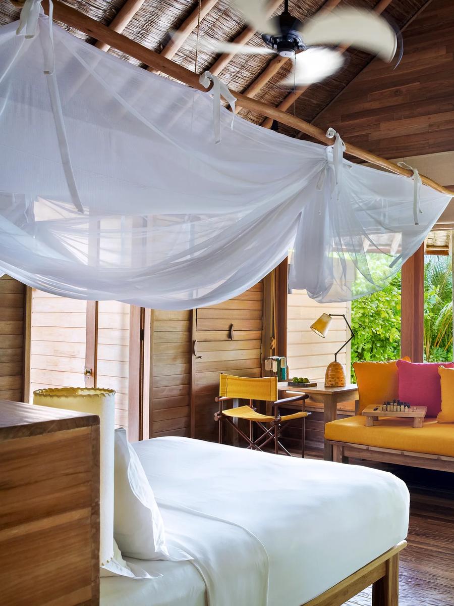 A ceiling fan turning beneath a thatched roof inside a beach villa with pool, representative of the lagoon-side category