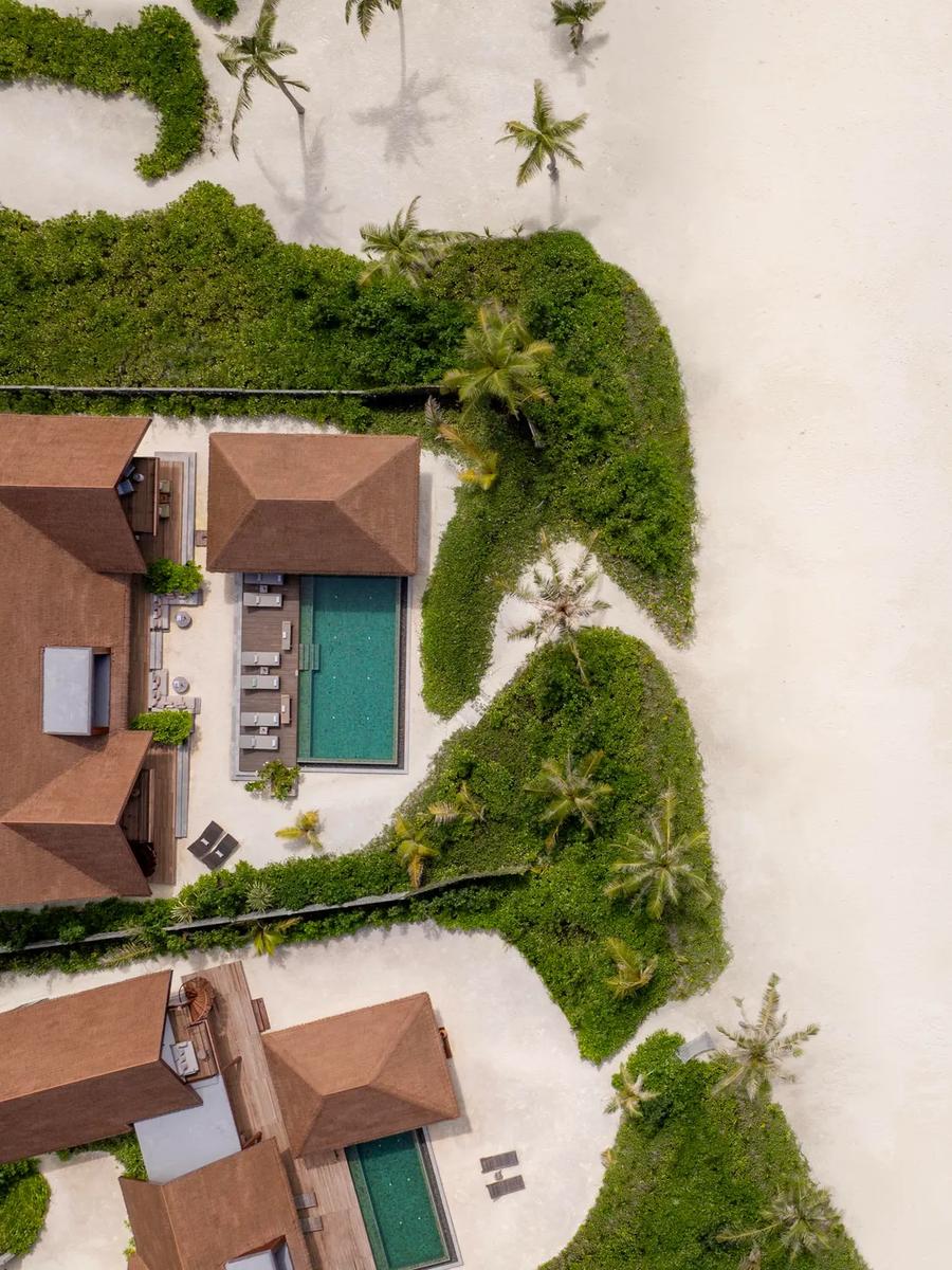 Aerial view of two large beachfront villas, each with a private pool, framed by garden and beach.