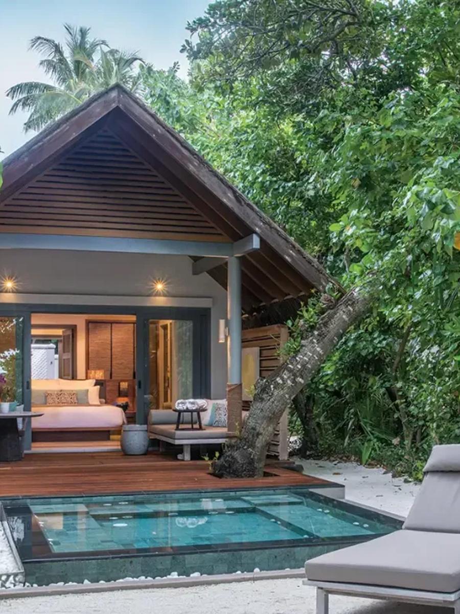 A thatched-roof Beach Villa with Plunge Pool set among jungle trees, its private pool and sun loungers on a sand terrace