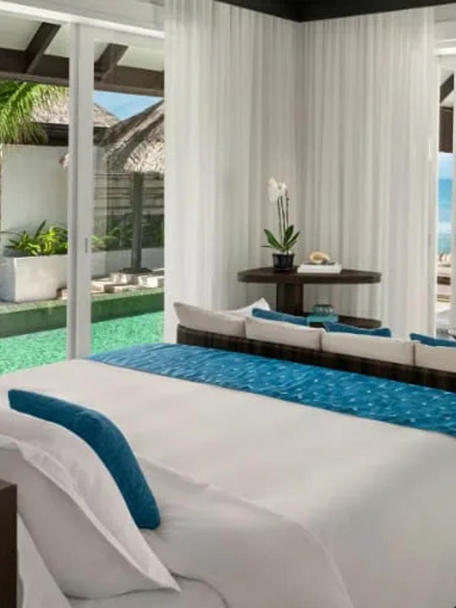 A Two-Bedroom Ocean House with Pool's bedroom opening onto the pool deck, a hanging swing daybed on the ocean-view terrace beyond
