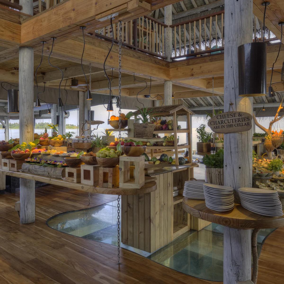 The vaulted timber-and-thatch roof of Longitude's double-height dining pavilion, with pendant lights and hanging chains