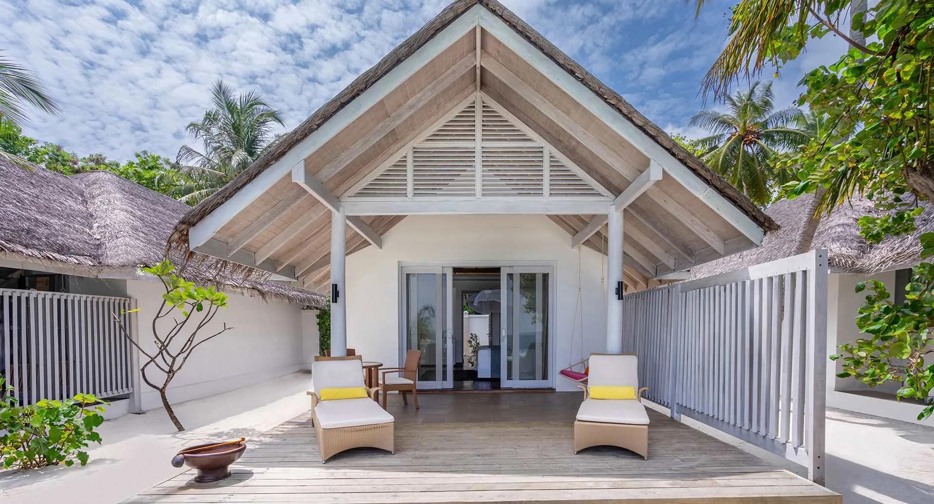 The exterior of a Beach Villa with Private Pool, its gabled thatched roof and deck loungers