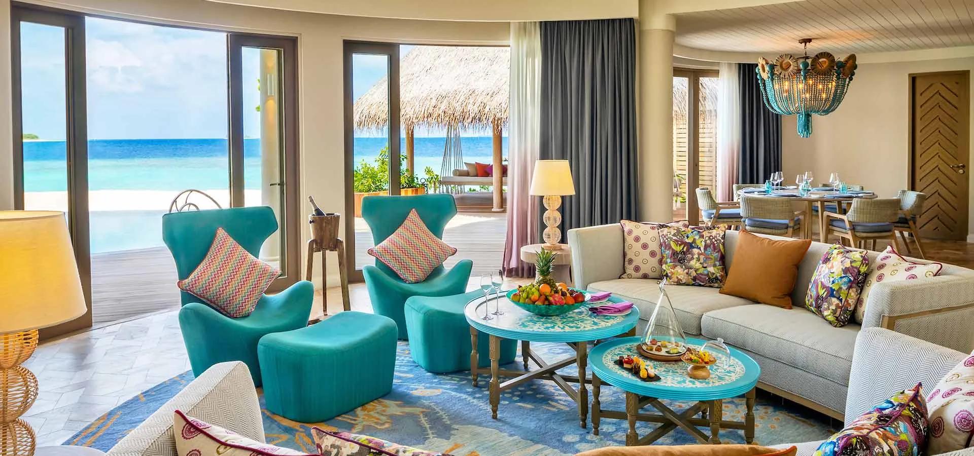 The Nautilus Mansion's living and dining room, its doors folded back to a swing seat, palm trees and open water.