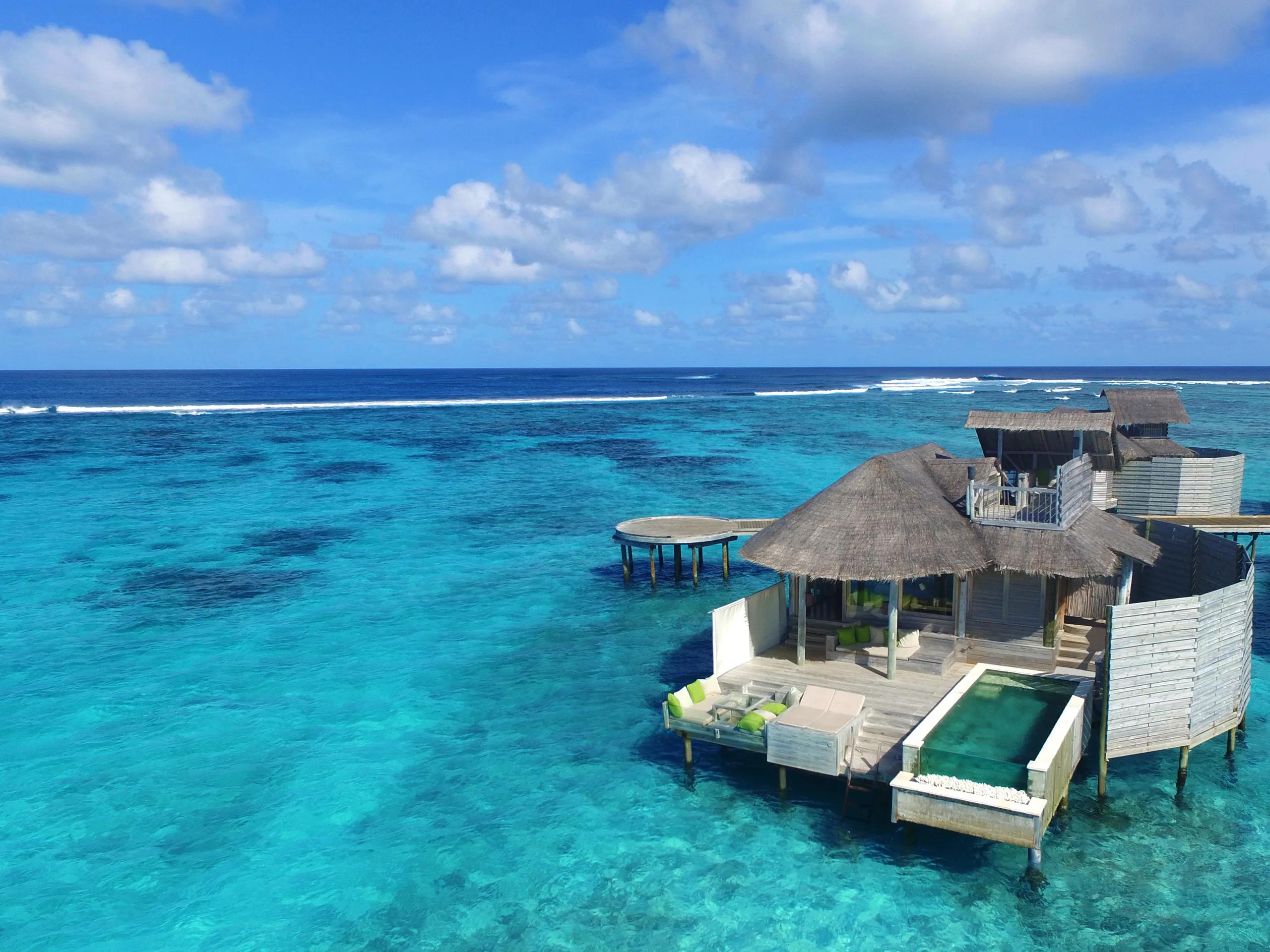 An aerial daytime view of an overwater villa and its private pool set over the lagoon, representative of Six Senses Laamu's water villa design