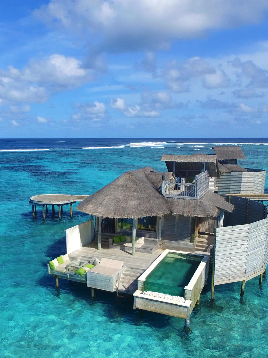 An aerial daytime view of an overwater villa and its private pool set over the lagoon, representative of Six Senses Laamu's water villa design