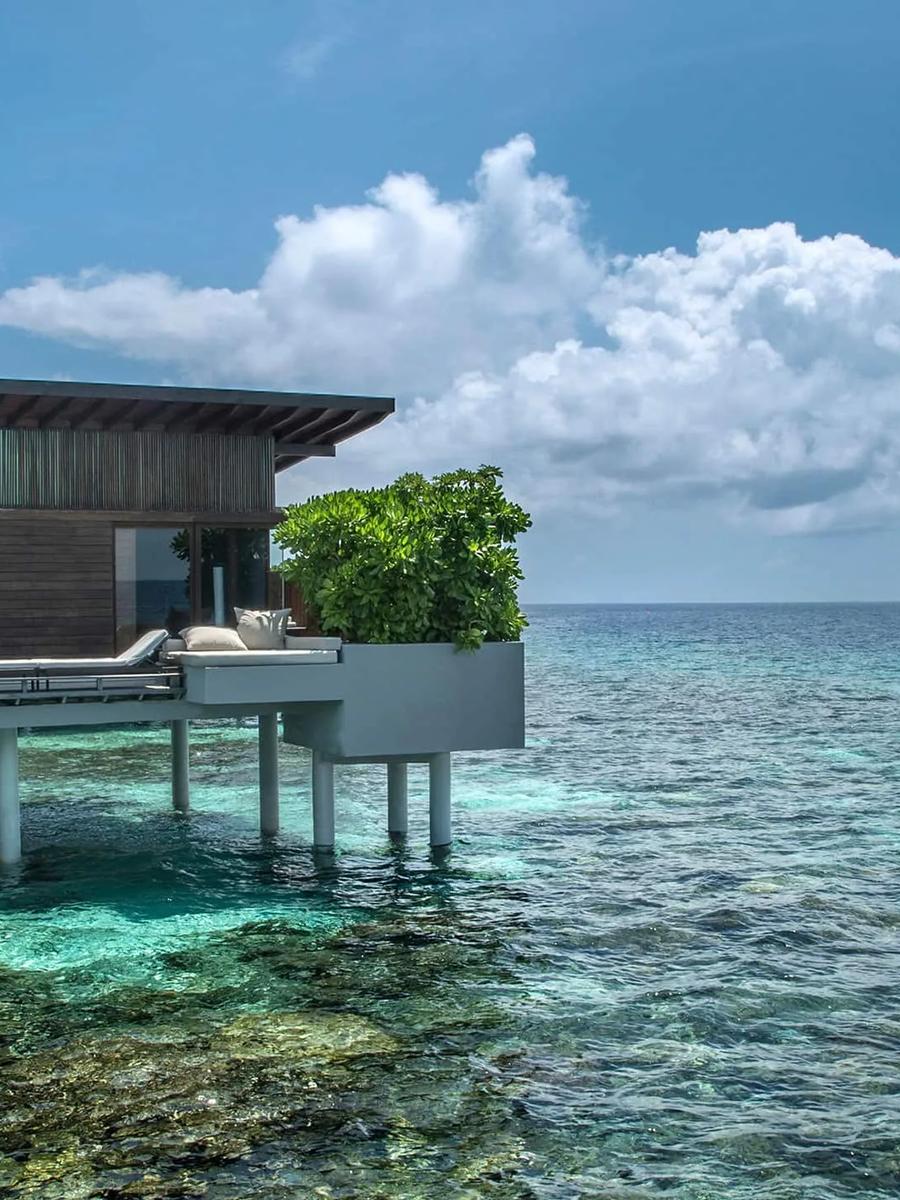 An Overwater Villa's private deck with sun loungers, set directly above the reef
