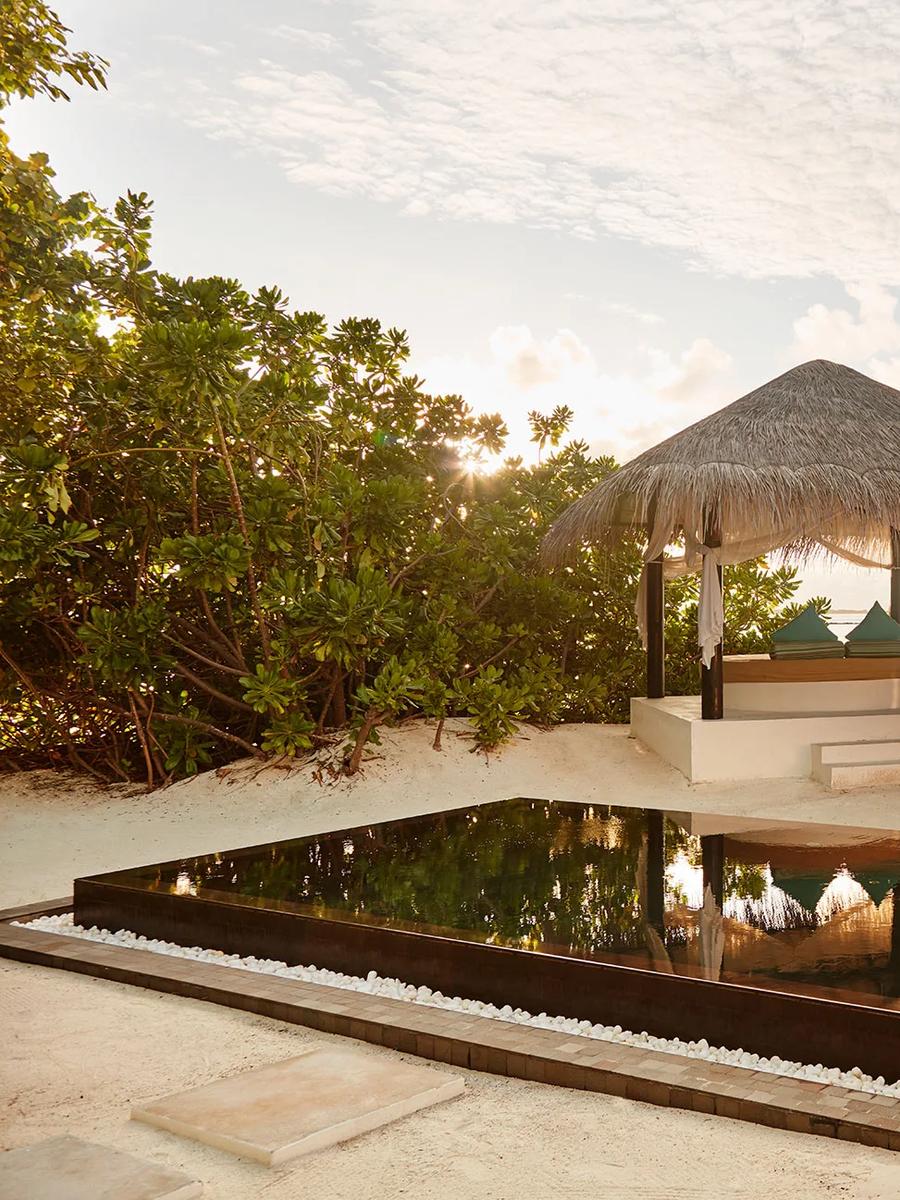 A private plunge pool and thatched beach sala lit by sunset, steps from the sand at a Family Deluxe Beach Villa with Pool