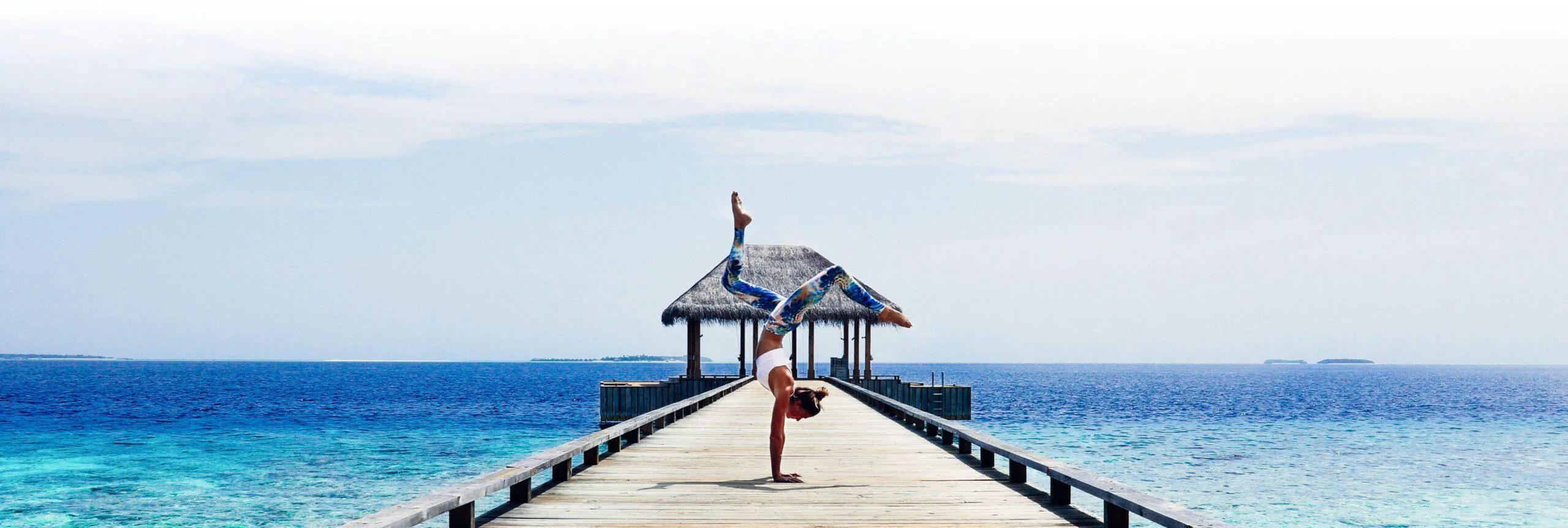 A yoga handstand on the jetty leading to Amilla's Overwater Spa Pavilion, open ocean either side