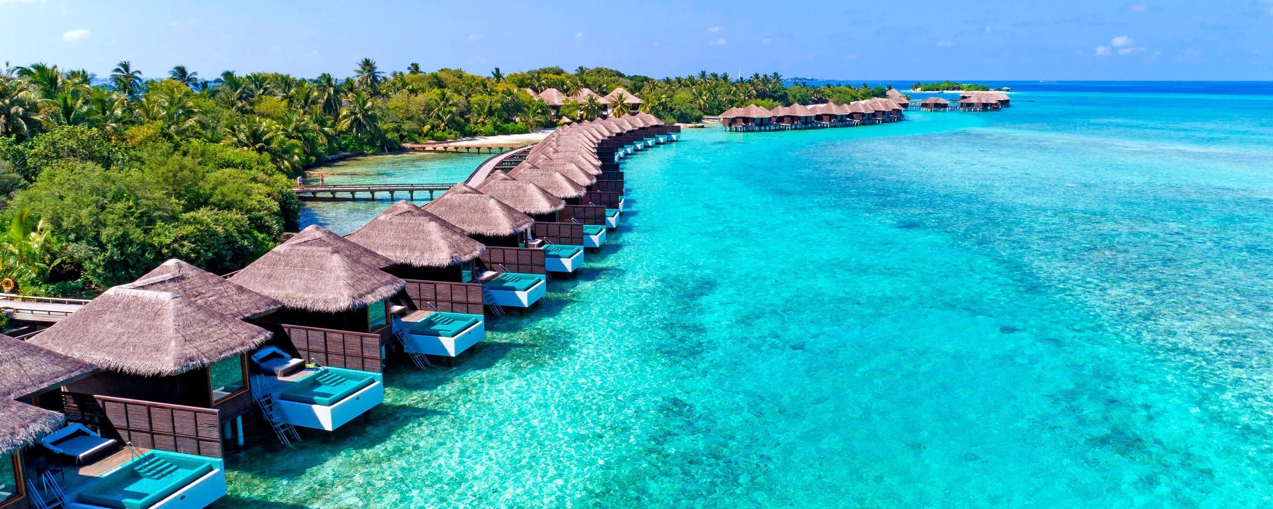 Aerial view of the overwater villa row at Sheraton Maldives Full Moon Resort & Spa, private plunge pools lining the lagoon-facing deck of each villa