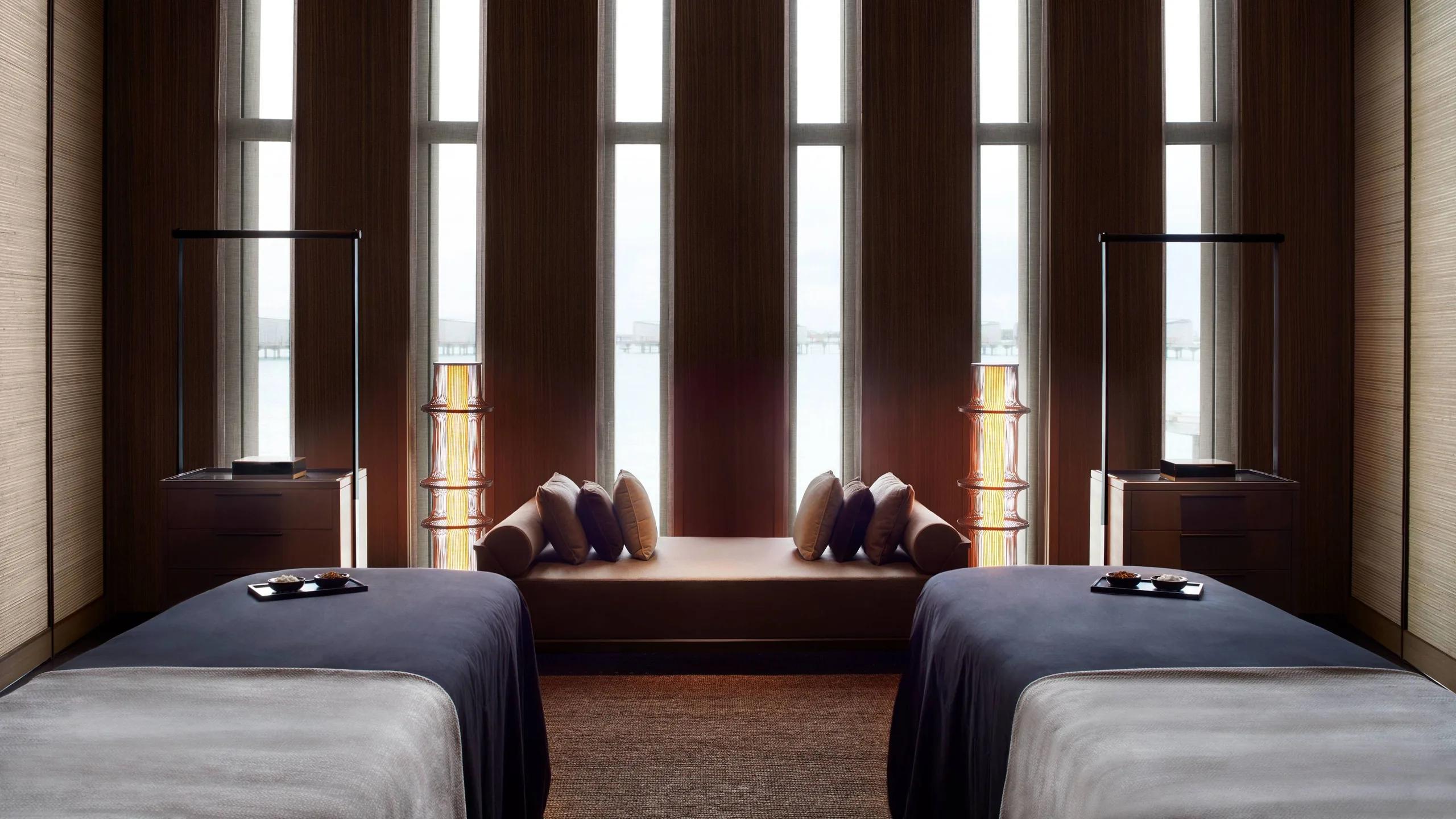 Two treatment beds facing floor-to-ceiling windows over the lagoon at The Ritz-Carlton Spa
