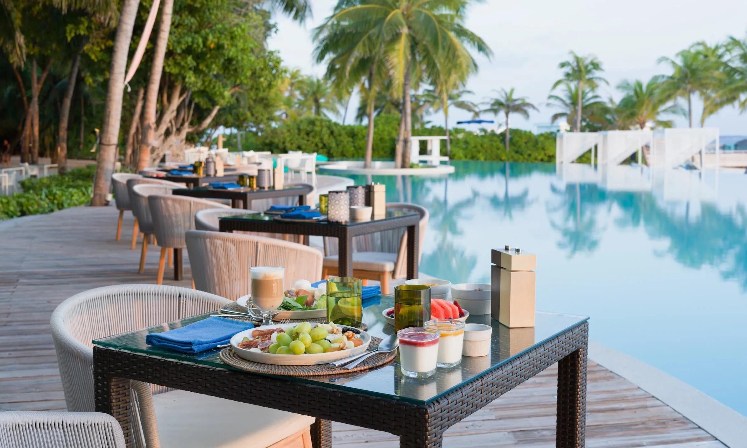 A poolside dining terrace at Amilla set for a meal; a dedicated photograph of Tessera, the resort's Arabian-inspired restaurant, was not available in this research pool