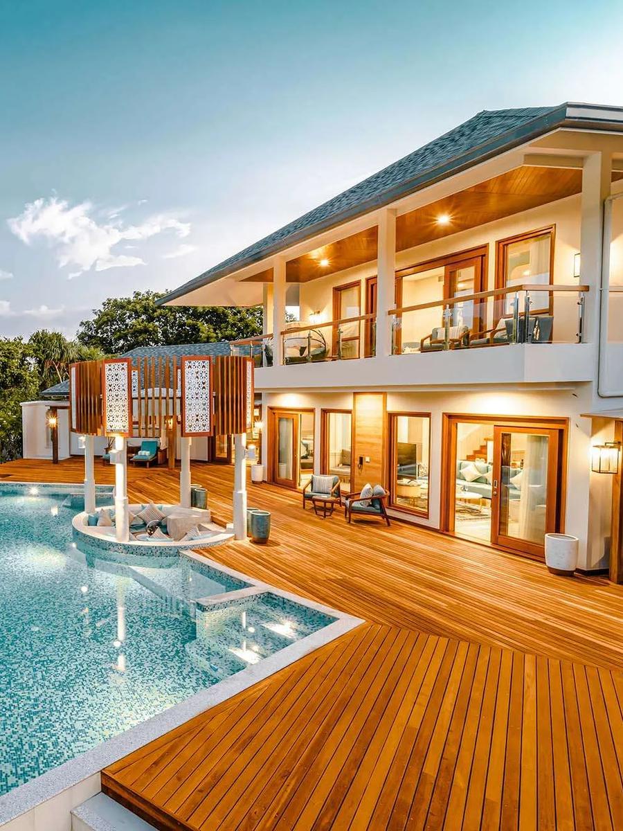 Twilight exterior of the Three-Bedroom Grand Beach Residence, its pool and two-storey villa lit warm against the dusk sky