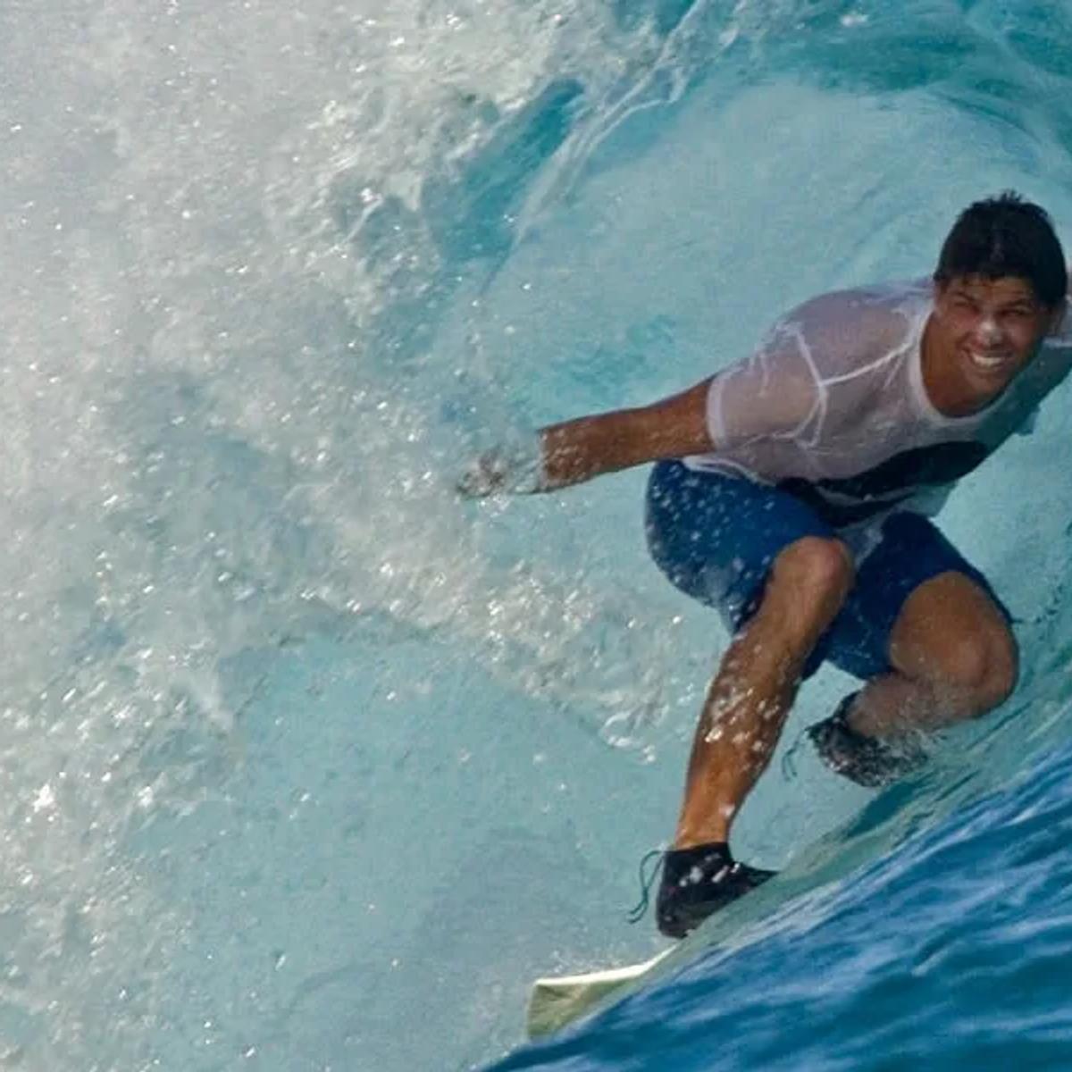 A surfer riding a wave near a Maldives resort