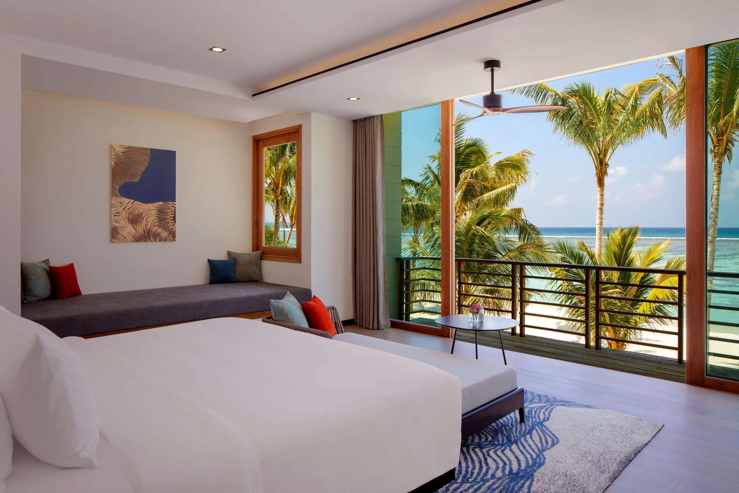 The bedroom and balcony of a Two Bedroom Family Villa at Radisson Blu Resort Maldives, overlooking the beach and lagoon