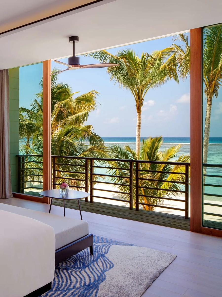The bedroom and balcony of a Two Bedroom Family Villa at Radisson Blu Resort Maldives, overlooking the beach and lagoon