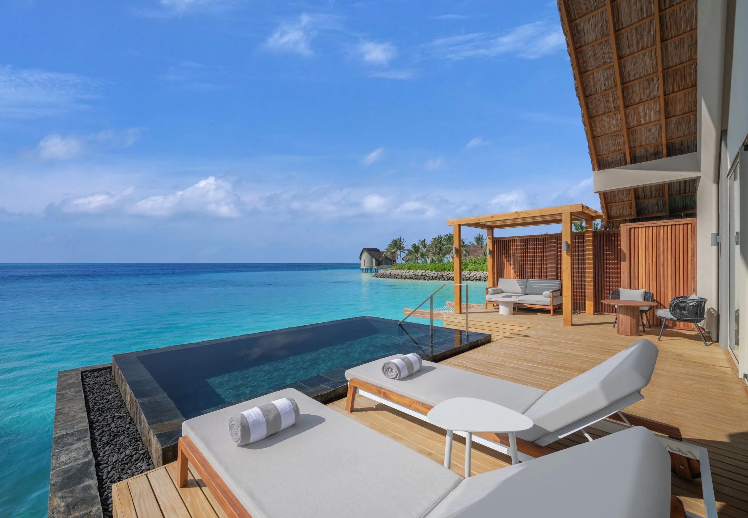 The pool deck of an overwater villa, lagoon stretching out beyond