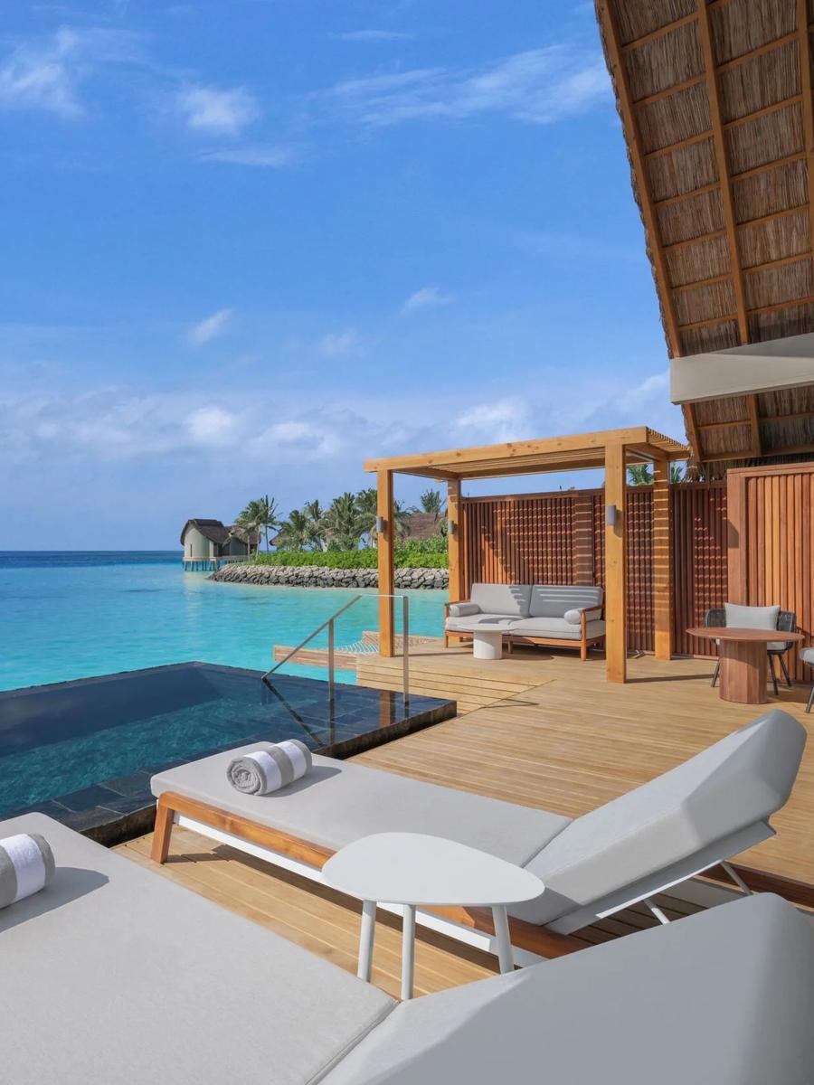 The pool deck of an overwater villa, lagoon stretching out beyond