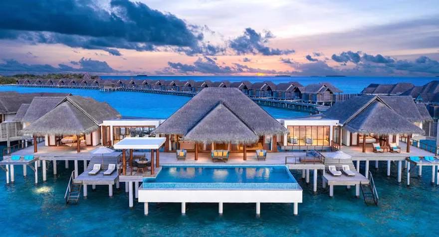 Two Bedroom Sunset Over Water Pool Residence at Anantara Kihavah, its pool and the overwater villa row beyond lit at dusk